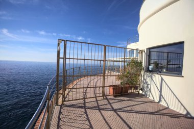 Güneşli bir günde ufka kadar uzanan bir uçurumun üzerindeki kapalı bir restoranın panoramik terasına çıkan bir binanın çitindeki kapalı kapı.