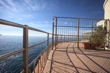 Güneşli bir günde ufka kadar uzanan bir uçurumun üzerindeki kapalı bir restoranın panoramik terasına çıkan bir binanın çitindeki kapalı kapı.