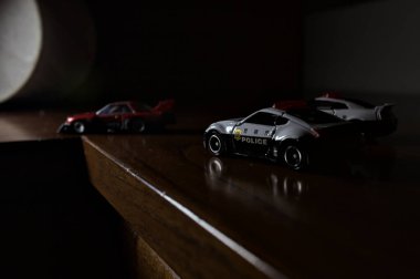 Cenova, İtalya - 20th NOVEMBER 2025 - Nissan Skyline Turbo Super Silueti 'nin kırmızı ve siyah yarış kıyafetleri içindeki Takara Tomi kopyaları Nissan Skyline GT-R R34 ve Japon polis üniformalarındaki Nissan Fairlady 350Z al