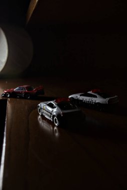 Cenova, İtalya - 20th NOVEMBER 2025 - Nissan Skyline Turbo Super Silueti 'nin kırmızı ve siyah yarış kıyafetleri içindeki Takara Tomi kopyaları Nissan Skyline GT-R R34 ve Japon polis üniformalarındaki Nissan Fairlady 350Z al