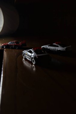 Cenova, İtalya - 20th NOVEMBER 2025 - Nissan Skyline Turbo Super Silueti 'nin kırmızı ve siyah yarış kıyafetleri içindeki Takara Tomi kopyaları Nissan Skyline GT-R R34 ve Japon polis üniformalarındaki Nissan Fairlady 350Z al