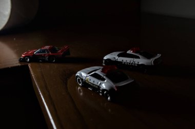 Cenova, İtalya - 20th NOVEMBER 2025 - Nissan Skyline Turbo Super Silueti 'nin kırmızı ve siyah yarış kıyafetleri içindeki Takara Tomi kopyaları Nissan Skyline GT-R R34 ve Japon polis üniformalarındaki Nissan Fairlady 350Z al