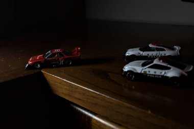 Cenova, İtalya - 20th NOVEMBER 2025 - Nissan Skyline Turbo Super Silueti 'nin kırmızı ve siyah yarış kıyafetleri içindeki Takara Tomi kopyaları Nissan Skyline GT-R R34 ve Japon polis üniformalarındaki Nissan Fairlady 350Z al