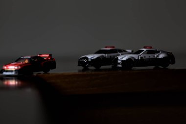 Cenova, İtalya - 20th NOVEMBER 2025 - Nissan Skyline Turbo Super Silueti 'nin kırmızı ve siyah yarış kıyafetleri içindeki Takara Tomi kopyaları Nissan Skyline GT-R R34 ve Japon polis üniformalarındaki Nissan Fairlady 350Z al