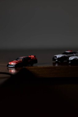 Cenova, İtalya - 20th NOVEMBER 2025 - Nissan Skyline Turbo Super Silueti 'nin kırmızı ve siyah yarış kıyafetleri içindeki Takara Tomi kopyaları Nissan Skyline GT-R R34 ve Japon polis üniformalarındaki Nissan Fairlady 350Z al