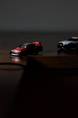 Cenova, İtalya - 20th NOVEMBER 2025 - Nissan Skyline Turbo Super Silueti 'nin kırmızı ve siyah yarış kıyafetleri içindeki Takara Tomi kopyaları Nissan Skyline GT-R R34 ve Japon polis üniformalarındaki Nissan Fairlady 350Z al