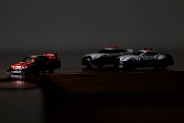 Cenova, İtalya - 20th NOVEMBER 2025 - Nissan Skyline Turbo Super Silueti 'nin kırmızı ve siyah yarış kıyafetleri içindeki Takara Tomi kopyaları Nissan Skyline GT-R R34 ve Japon polis üniformalarındaki Nissan Fairlady 350Z al