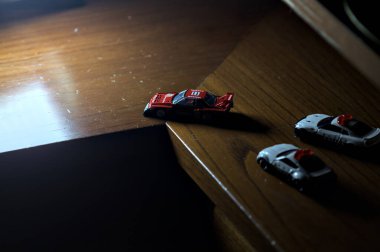 Cenova, İtalya - 20th NOVEMBER 2025 - Nissan Skyline Turbo Super Silueti 'nin kırmızı ve siyah yarış kıyafetleri içindeki Takara Tomi kopyaları Nissan Skyline GT-R R34 ve Japon polis üniformalarındaki Nissan Fairlady 350Z al