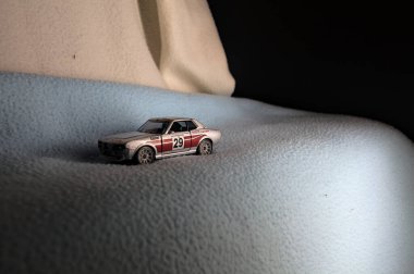 Mantova, İtalya - 14 ARALIK 2025 - Bir Toyota Celica GT Coupein gümüşü ve bir uçurumun kenarındaki karlı yolda koşuyormuş gibi yapan kırmızı üniformanın kopyası