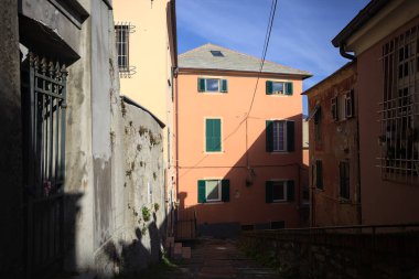 Staircase bordered by a concrete railing between houses on a cliff partially lit by the sun