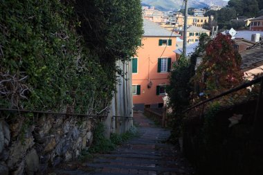 Merdiven, evlerin arasında beton bir korkulukla çevrili. Kısmen güneş gören bir uçurumun kenarında.