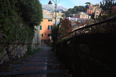 Merdiven, evlerin arasında beton bir korkulukla çevrili. Kısmen güneş gören bir uçurumun kenarında.