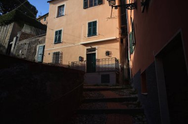 Merdiven, evlerin arasında beton bir korkulukla çevrili. Kısmen güneş gören bir uçurumun kenarında.