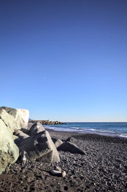 Foreshore by the sea on a sunny day with clear sky framed by rocks by the edge of a beach