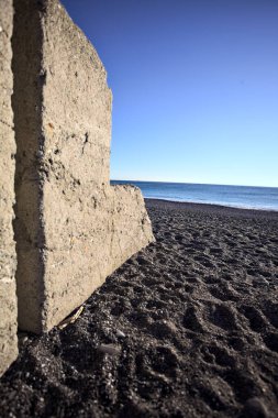 Foreshore of a beach at sunset framed by the portion of a concrete wall