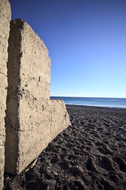 Foreshore of a beach at sunset framed by the portion of a concrete wall