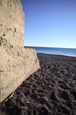 Foreshore of a beach at sunset framed by the portion of a concrete wall
