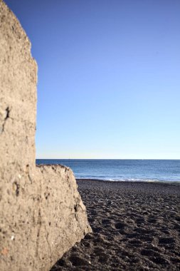Foreshore of a beach at sunset framed by the portion of a concrete wall