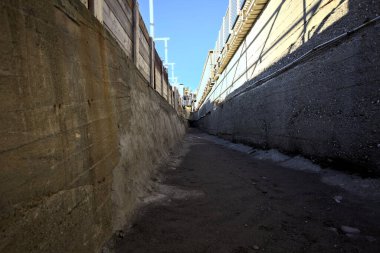 Dry concrete channel seen from below lit on its top by the sun
