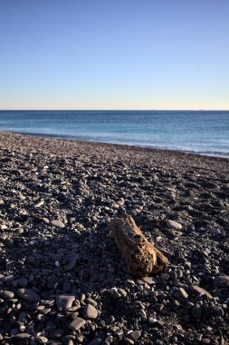 Drywood gün batımında çakıl taşlı bir plajda yatıyor. Sahilin hemen yanında.