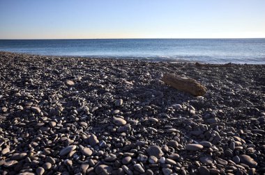Drywood gün batımında çakıl taşlı bir plajda yatıyor. Sahilin hemen yanında.