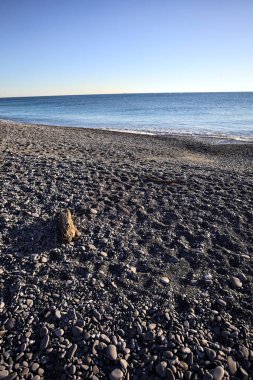 Drywood gün batımında çakıl taşlı bir plajda yatıyor. Sahilin hemen yanında.