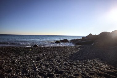 Gölgede kayalar ve gün batımında kayaların üzerinde filtrelenen güneş ışığı grubu.