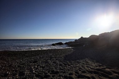 Gölgede kayalar ve gün batımında kayaların üzerinde filtrelenen güneş ışığı grubu.