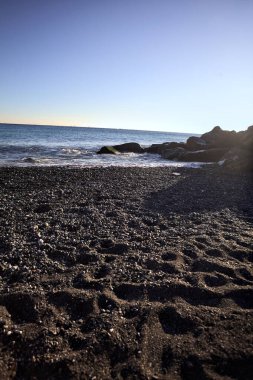 Gölgede kayalar ve gün batımında kayaların üzerinde filtrelenen güneş ışığı grubu.