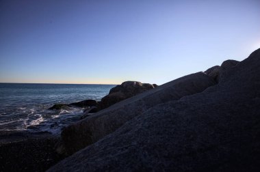 Gölgede kayalar ve gün batımında kayaların üzerinde filtrelenen güneş ışığı grubu.