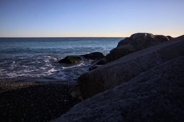 Gölgede kayalar ve gün batımında kayaların üzerinde filtrelenen güneş ışığı grubu.