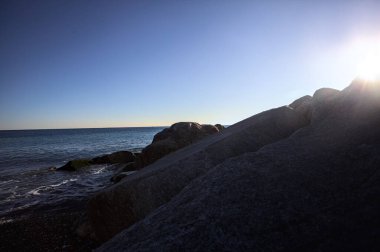 Gölgede kayalar ve gün batımında kayaların üzerinde filtrelenen güneş ışığı grubu.