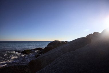 Gölgede kayalar ve gün batımında kayaların üzerinde filtrelenen güneş ışığı grubu.