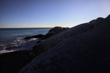 Gölgede kayalar ve gün batımında kayaların üzerinde filtrelenen güneş ışığı grubu.