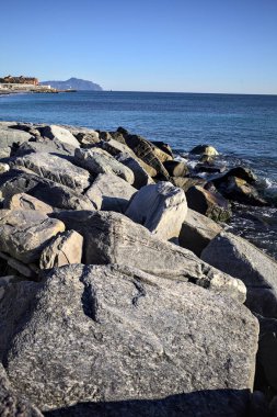 Küçük bir körfezden görünen ve dalgakıran kayaları tarafından çerçevelenen binalar ve uçurumun kenarındaki bir çıkıntının ucu.