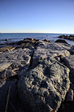 Rocks of a cliff at sunset seen at water level with the sea stretching to the Horizon