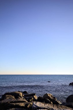 Rocks of a cliff at sunset seen at water level with the sea stretching to the Horizon