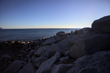 Gölgede kayalar ve gün batımında kayaların üzerinde filtrelenen güneş ışığı grubu.