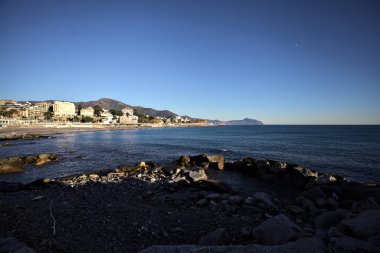 Deniz kenarındaki bina ve bulvar. Denizin üzerindeki küçük bir uçurumdan görülebiliyor. Kışın gün batımında sahneyi çerçeveliyorlar.
