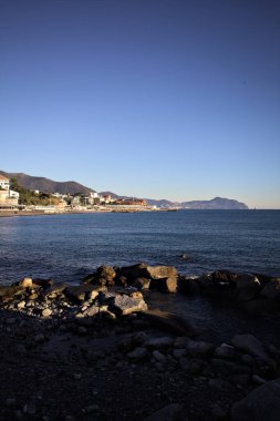 Deniz kenarındaki bina ve bulvar. Denizin üzerindeki küçük bir uçurumdan görülebiliyor. Kışın gün batımında sahneyi çerçeveliyorlar.