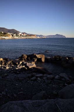 Deniz kenarındaki bina ve bulvar. Denizin üzerindeki küçük bir uçurumdan görülebiliyor. Kışın gün batımında sahneyi çerçeveliyorlar.