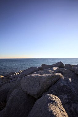 Rocks of a cliff at sunset seen at water level with the sea stretching to the Horizon