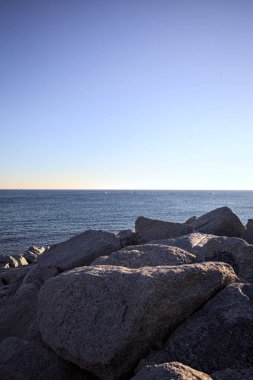 Gün batımında bir uçurumun kayaları su seviyesinde görülür ve deniz Horizon 'a kadar uzanır.