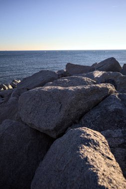 Gün batımında bir uçurumun kayaları su seviyesinde görülür ve deniz Horizon 'a kadar uzanır.