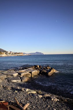 Küçük bir körfezden görünen ve dalgakıran kayaları tarafından çerçevelenen binalar ve uçurumun kenarındaki bir çıkıntının ucu.