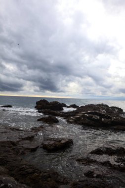 Alacakaranlıkta bulutlu bir günde, deniz kenarındaki bir körfezdeki kayanın yanındaki küçük merdivende.