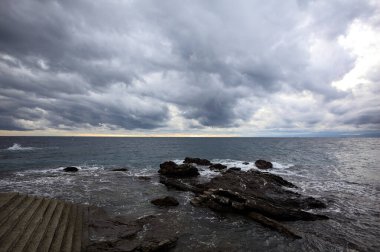 Bulutlu bir günde alacakaranlıkta kayaların yanında uçurumun kenarındaki merdiven.