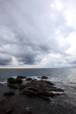 Alacakaranlıkta bulutlu bir günde, deniz kenarındaki bir körfezdeki kayanın yanındaki küçük merdivende.
