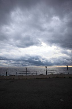 Üzerinde sokak lambası olan korkuluklar ve alacakaranlıkta ufka uzanan deniz.