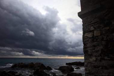 Deniz kıyısındaki bir viyadük kemerleri, bir dalgakıranın kayaları üzerinde, alacakaranlıkta bulutlu bir günde görülür.